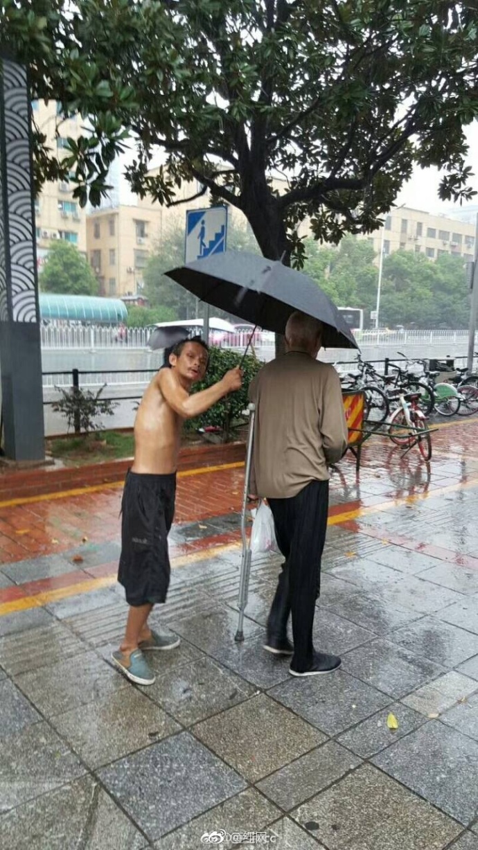 暴雨中 流浪乞丐为腿脚不便的老人撑伞(图)