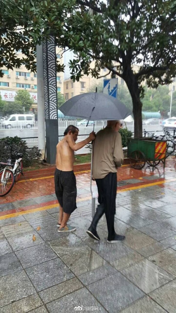 暴雨中 流浪乞丐为腿脚不便的老人撑伞(图)