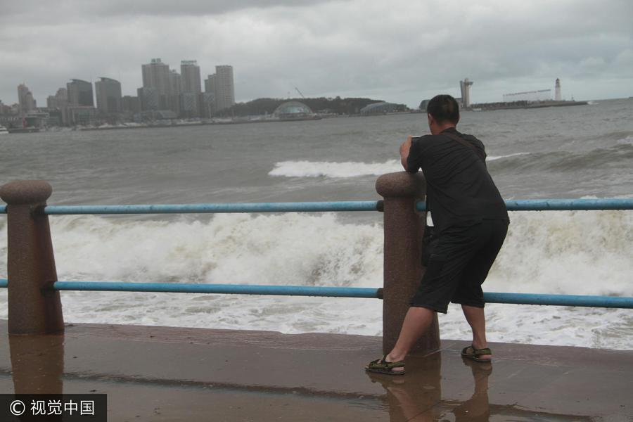 青岛国庆首日遇狂风 游客海边观潮捡海带