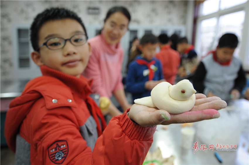 一名青岛长沙路小学的学生展示自己制作的面塑小燕子.