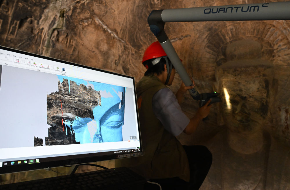 2025年4月9日，武汉大学文化遗产智能计算实验室团队成员在魏字洞使用关节臂扫描仪对佛像进行数字化扫描。图片来源新华社