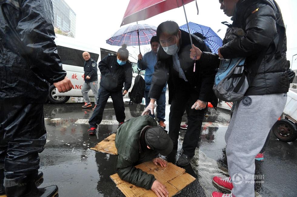 组图:青岛一老人路上摔倒 众人雨中为其撑伞