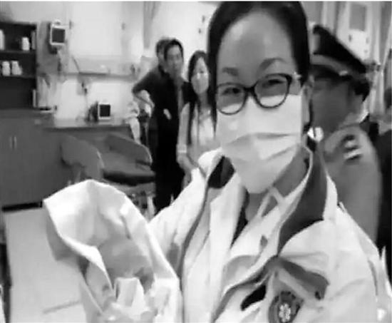 急救人员抱着抢救成功的女婴(视频截图)。