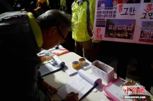10月29日晚，近两万名韩国民众及民间团体人士在首尔市中心举行烛光集会，谴责“亲信干政事件”给韩国社会带来的不良影响，要求总统朴槿惠对此事负责。图为民众在集会现场写下请愿书，要求查明事情真相。中新社记者 吴旭 摄