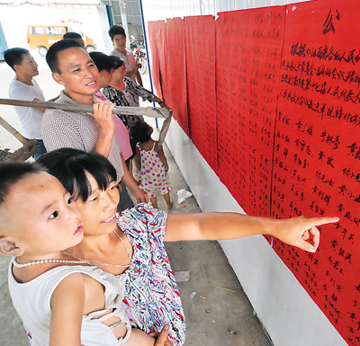 江西南丰县傅坊乡梅林村选民观看张榜公布的选民名单。