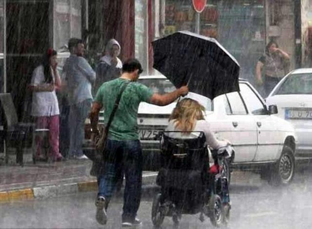 一名乐于助人的男子在下雨天将自己的伞打给坐在轮椅上的一名女子