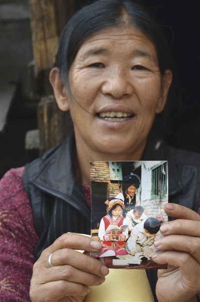 陆学英展示她与收养的四个孤儿的合照