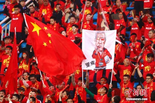 上周，国足在主场战胜韩国队，现场观众擎起中国队主教练里皮的漫画像。 中新社记者 富田 摄