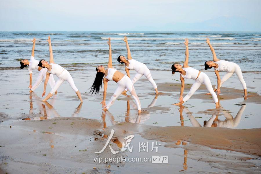  青岛瑜伽爱好者来到海边沙滩，在沙滩和海水中秀起瑜伽。