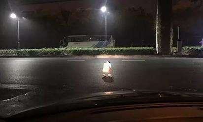 女子蹲在马路上，李先生用车灯照在她身边，直到民警赶到。 