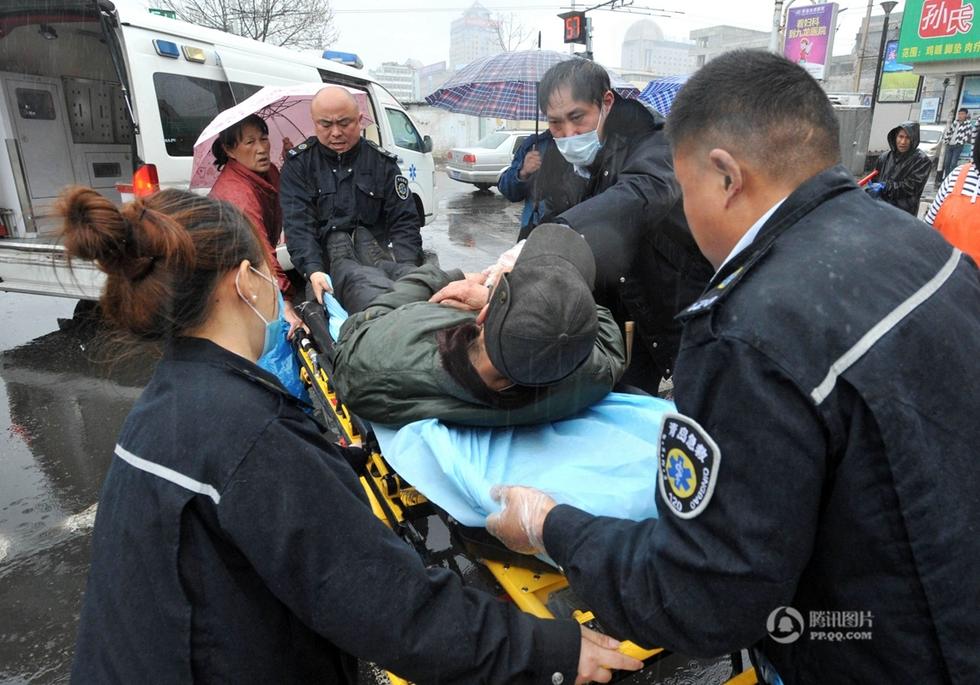 组图:青岛一老人路上摔倒 众人雨中为其撑伞