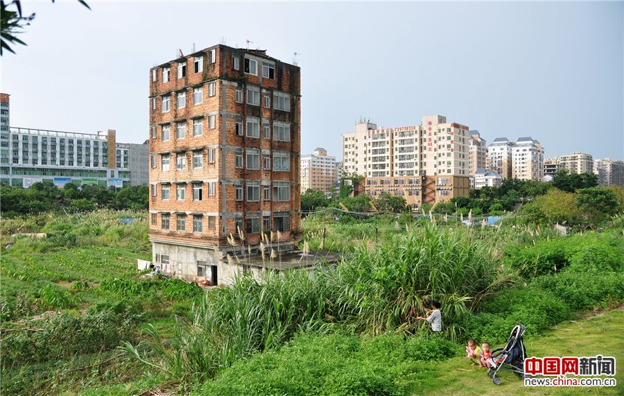 2016年6月13日，广东深圳，深圳龙华新区深圳北站附近，一栋墙体裸露红砖、显得破旧的七层小楼，孤零零地伫立在空地上，犹如一座孤岛，与远处的高楼形成巨大的反差。2011年，广深高铁开通，这栋950平米的建筑，曾被谈到2000多万的补偿款，由于屋主的拒绝，至今仍高耸至此。前不久（6月8日），龙华新区地理位置远不如此的一宗商住混合用地，成交价被拍出140.6亿元，晋升今年全国土地总价新地王。这栋犹如孤岛的七层小楼，重新回到公众的视野。