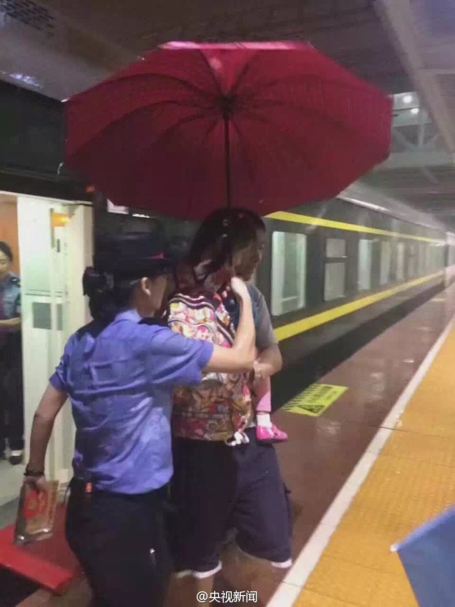 乘务员雨中撑伞护送旅客 浑身湿透