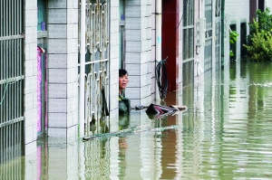 7月4日，江苏省常州市武进区前黄镇一名居民在家门口等待救援。新华社发
