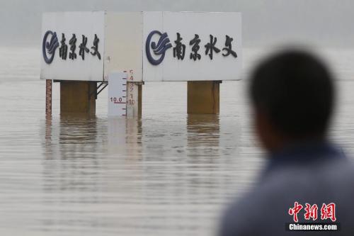 资料图：7月6日，一位市民在长江南京下关水文标尺前经过。当日，南京水文局发布的信息显示，长江水位上涨迅速，最高峰达9.8米，持续超过警戒线。中新社记者 泱波 摄