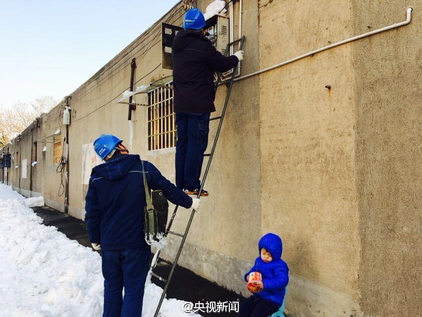 男孩雪地捧方便面睡着 父亲在旁修电路