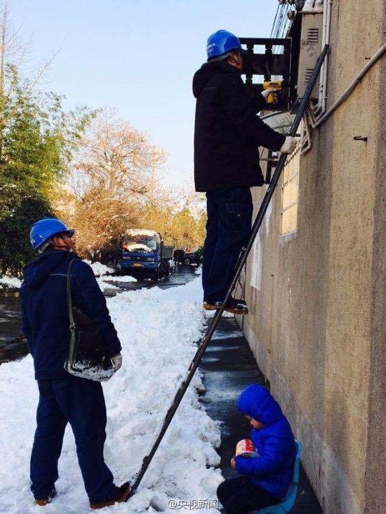 男孩雪地捧方便面睡着 父亲在旁修电路