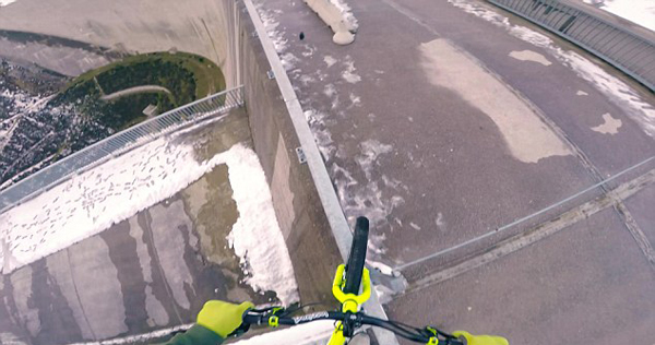 不要命!青年在奥地利200米高水坝顶端骑行(图)