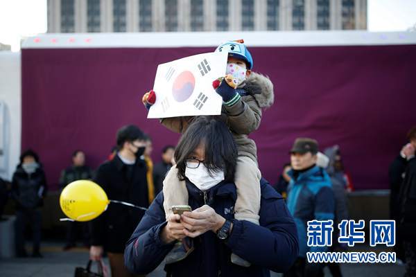 12月10日，首尔，一名儿童手持一面韩国国旗参加要求朴槿惠下台的游行。路透社/新华社