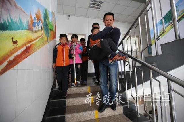青岛这个男娃骨折两个月 老师们轮流抱他上课