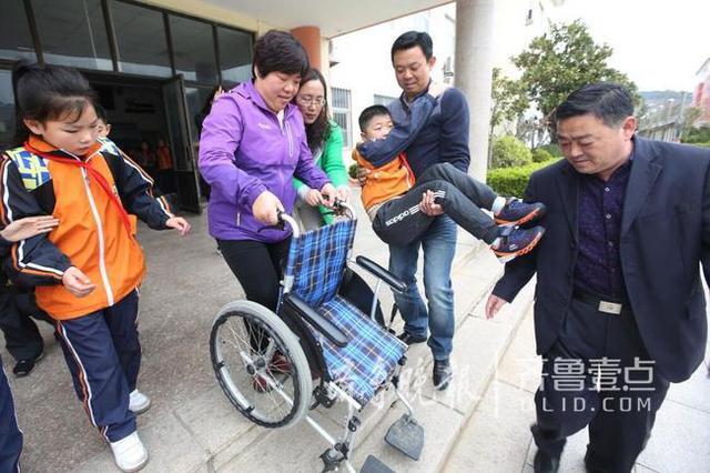 青岛这个男娃骨折两个月 老师们轮流抱他上课