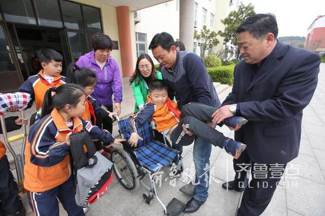 青岛这个男娃骨折两个月 老师们轮流抱他上课
