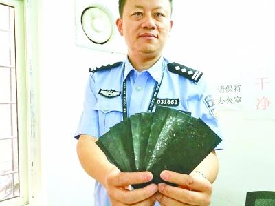 　　办案警察展示冒充“隐形美金”的黑纸